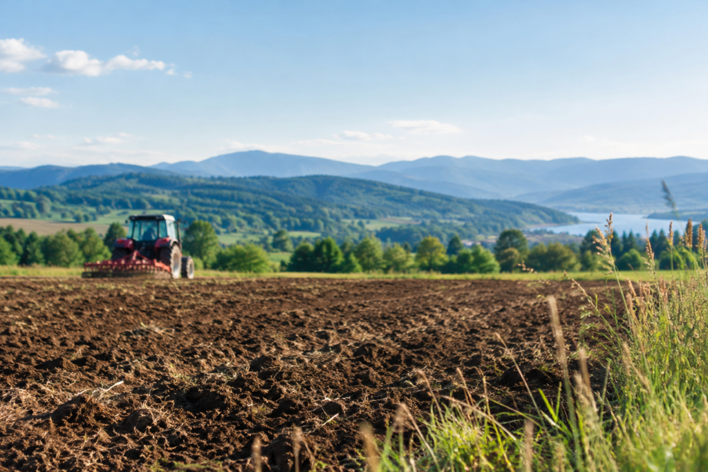 Sunlit Countryside with Tractor and Mountains